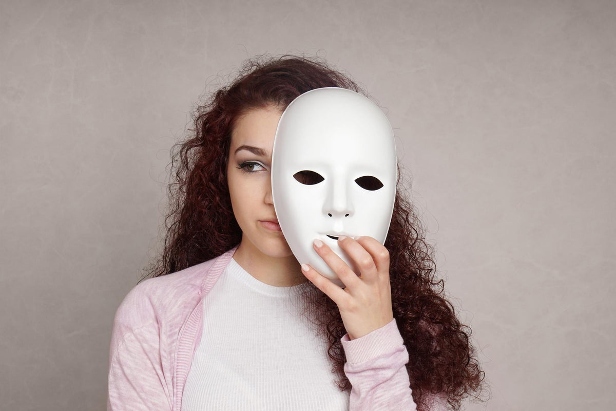 femme avec un masque blanc devant son visage qu'elle tient dans sa main