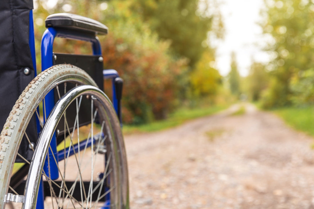 Gros plan sur la roue d'un fauteuil roulant sur un chemin en gravier, illustrant le remboursement des fauteuils roulants en 2026