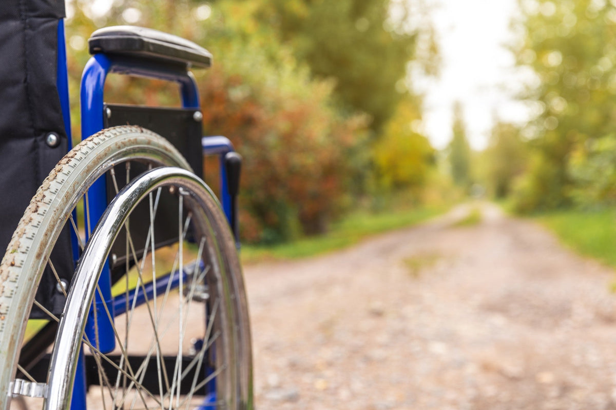 Gros plan sur la roue d'un fauteuil roulant sur un chemin en gravier, illustrant le remboursement des fauteuils roulants en 2026