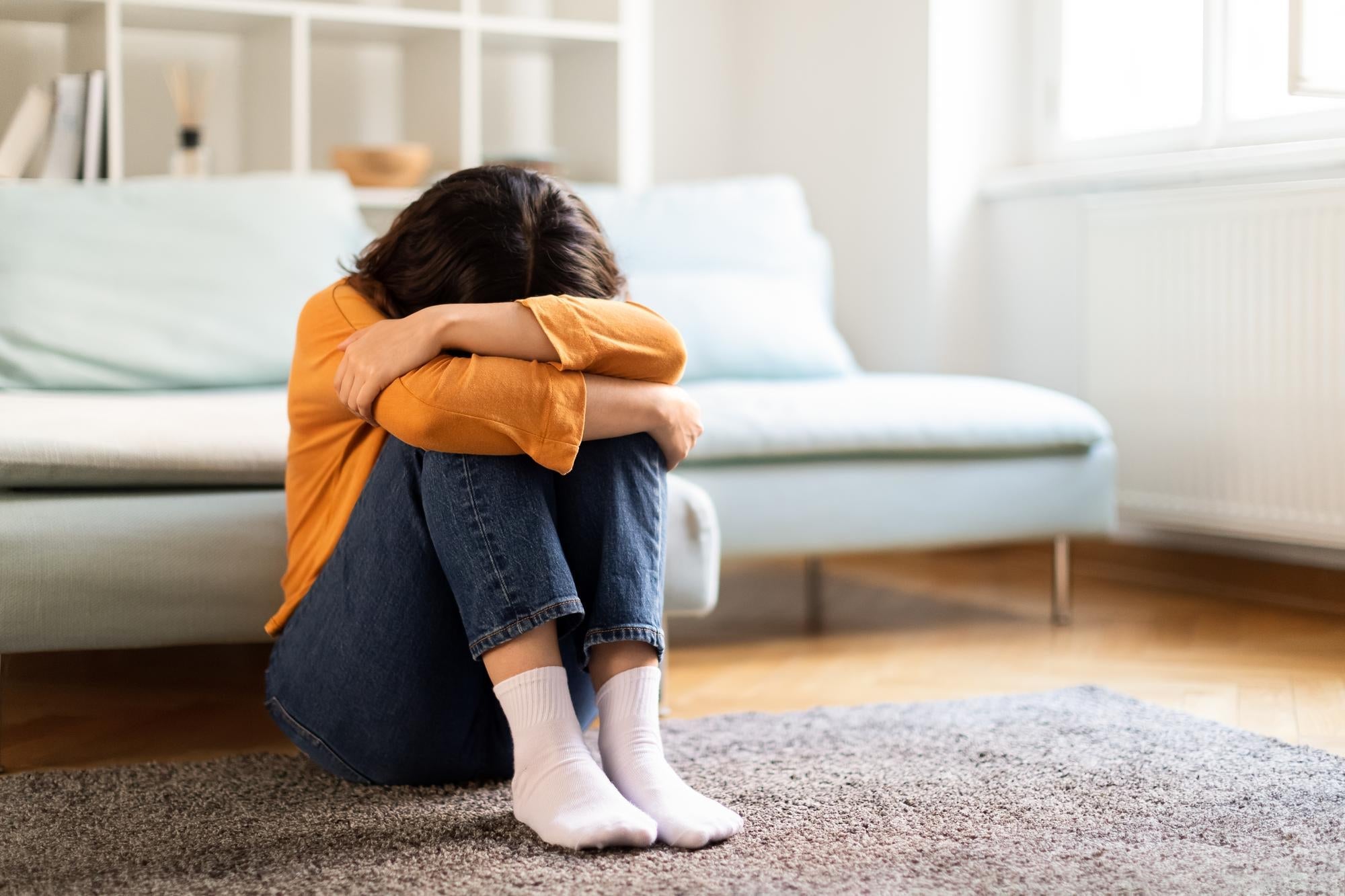 femme assise par terre qui a la tête dans ses bras