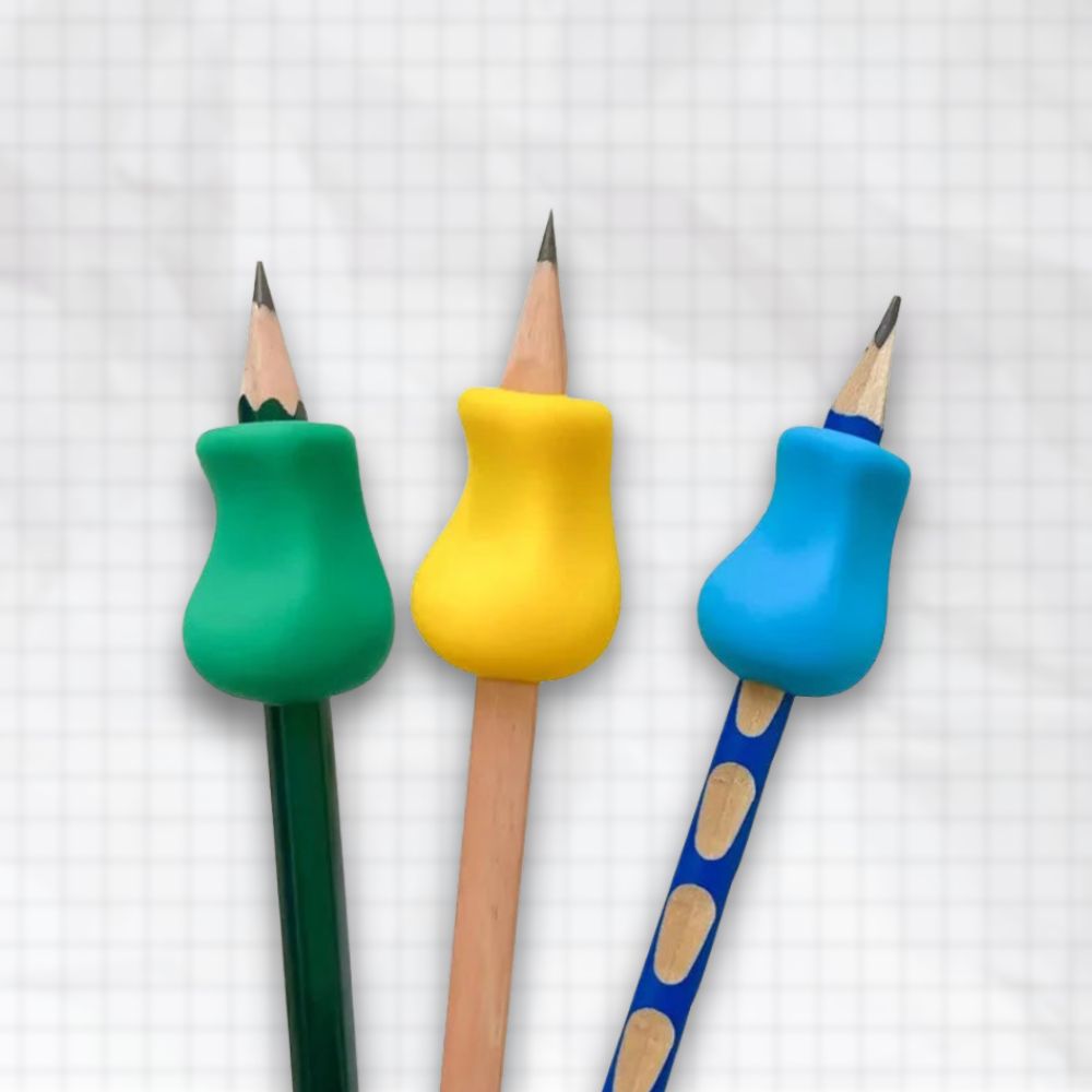 Trois crayons équipés de porte-crayons ergonomiques en silicone vert, jaune et bleu, posés sur fond quadrillé