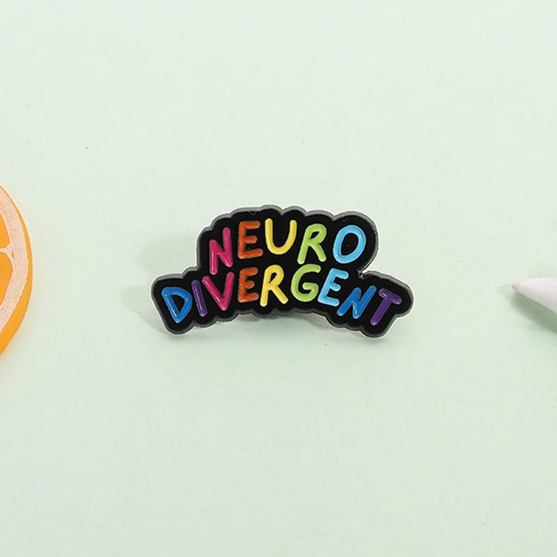 Gros plan sur l'émail coloré du pin's Neurodivergent, détail des lettres arc-en-ciel